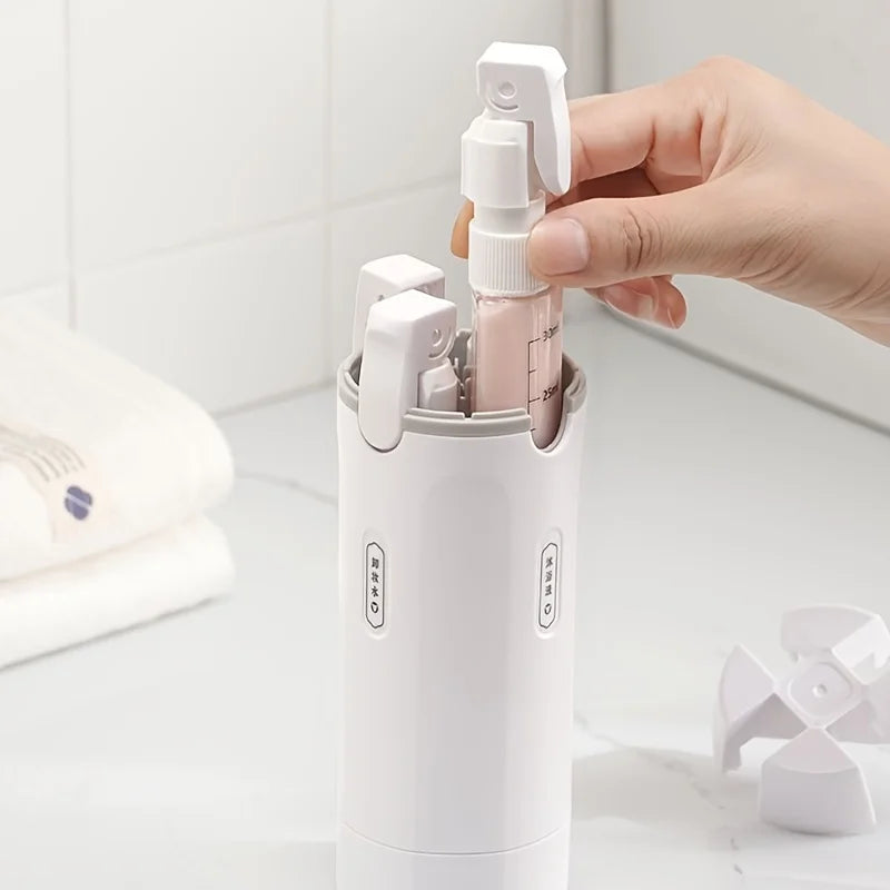 Hand holding a white spray bottle with a pink pump over a white container with multiple spray bottles.