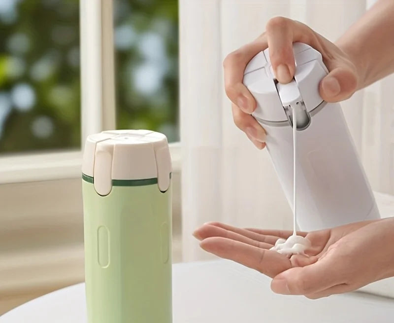 Person using a white bottle to dispense liquid soap into their hand, with a green container on a surface in the foreground.